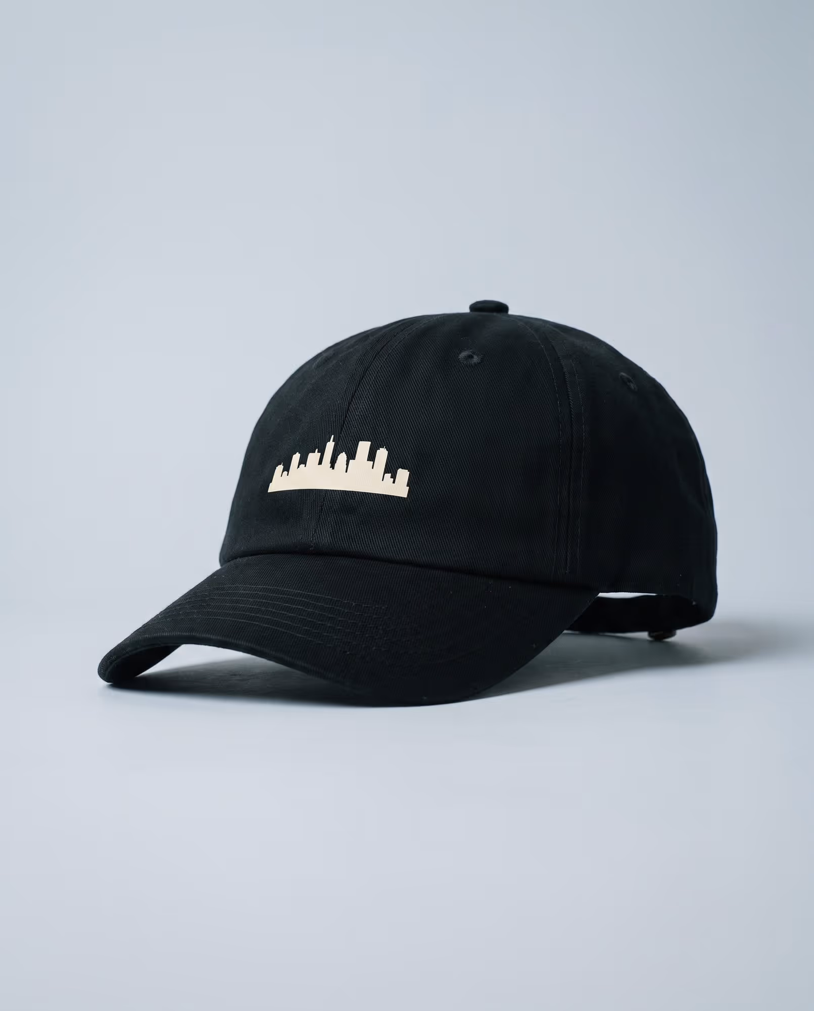 Black structured cap with a city skyline printed in cream on the front panel