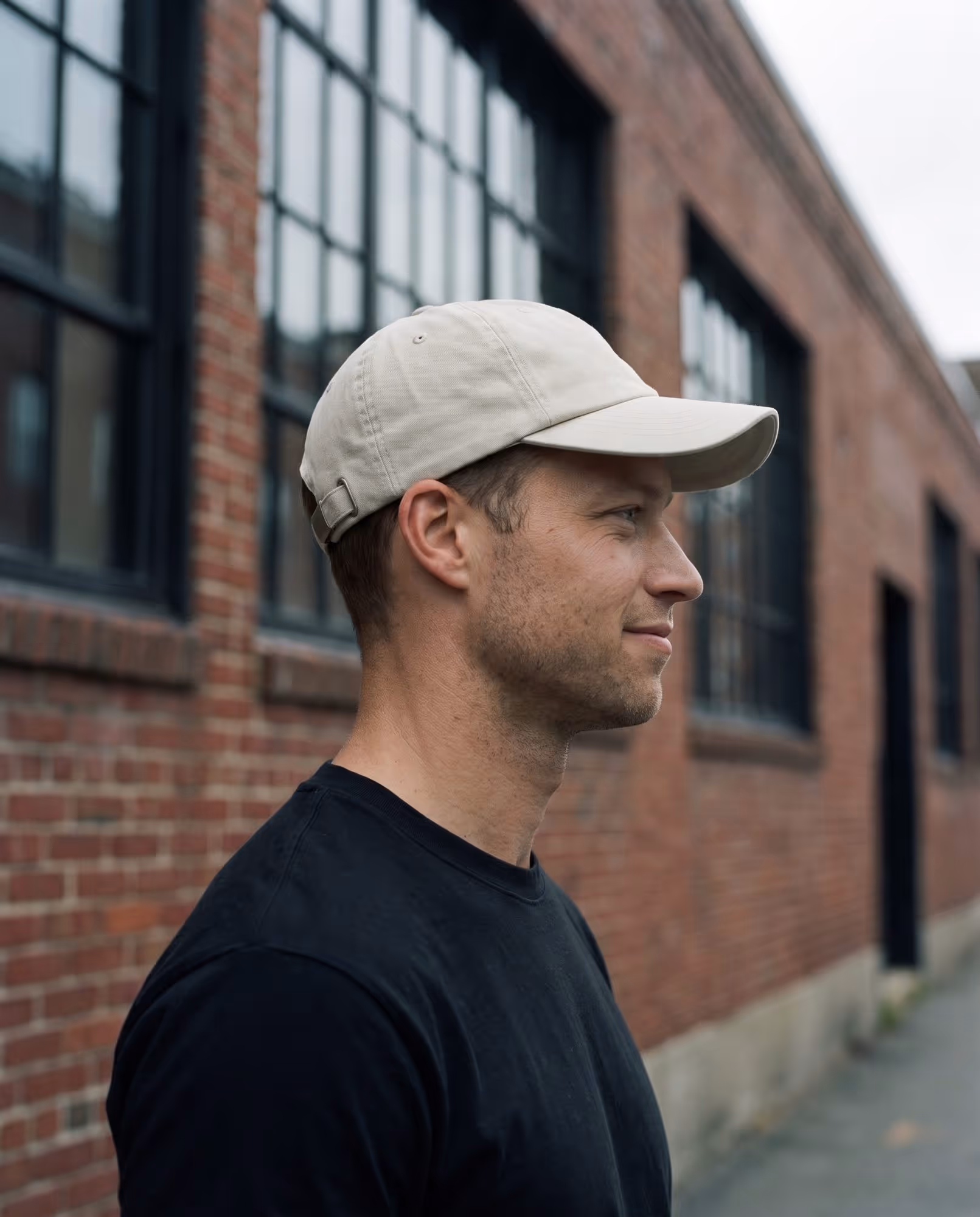 Model wearing a plain stone-coloured unstructured dad hat, photographed in profile
