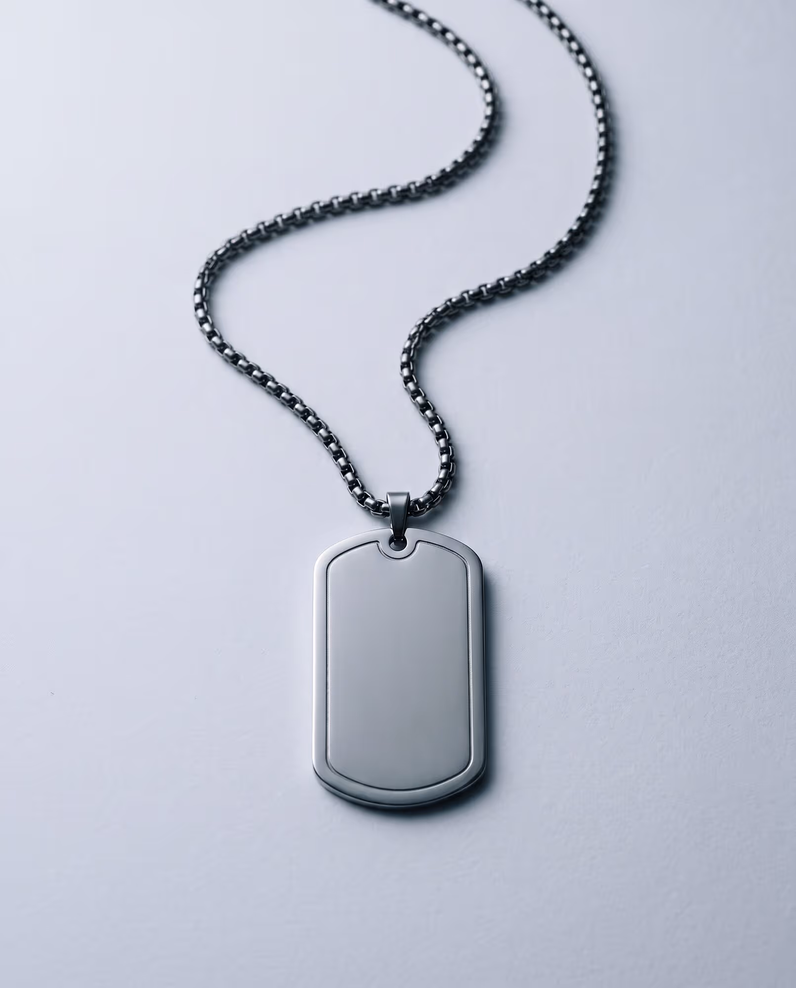 Blank silver-tone dog tag with a raised rim on a dark gunmetal box chain