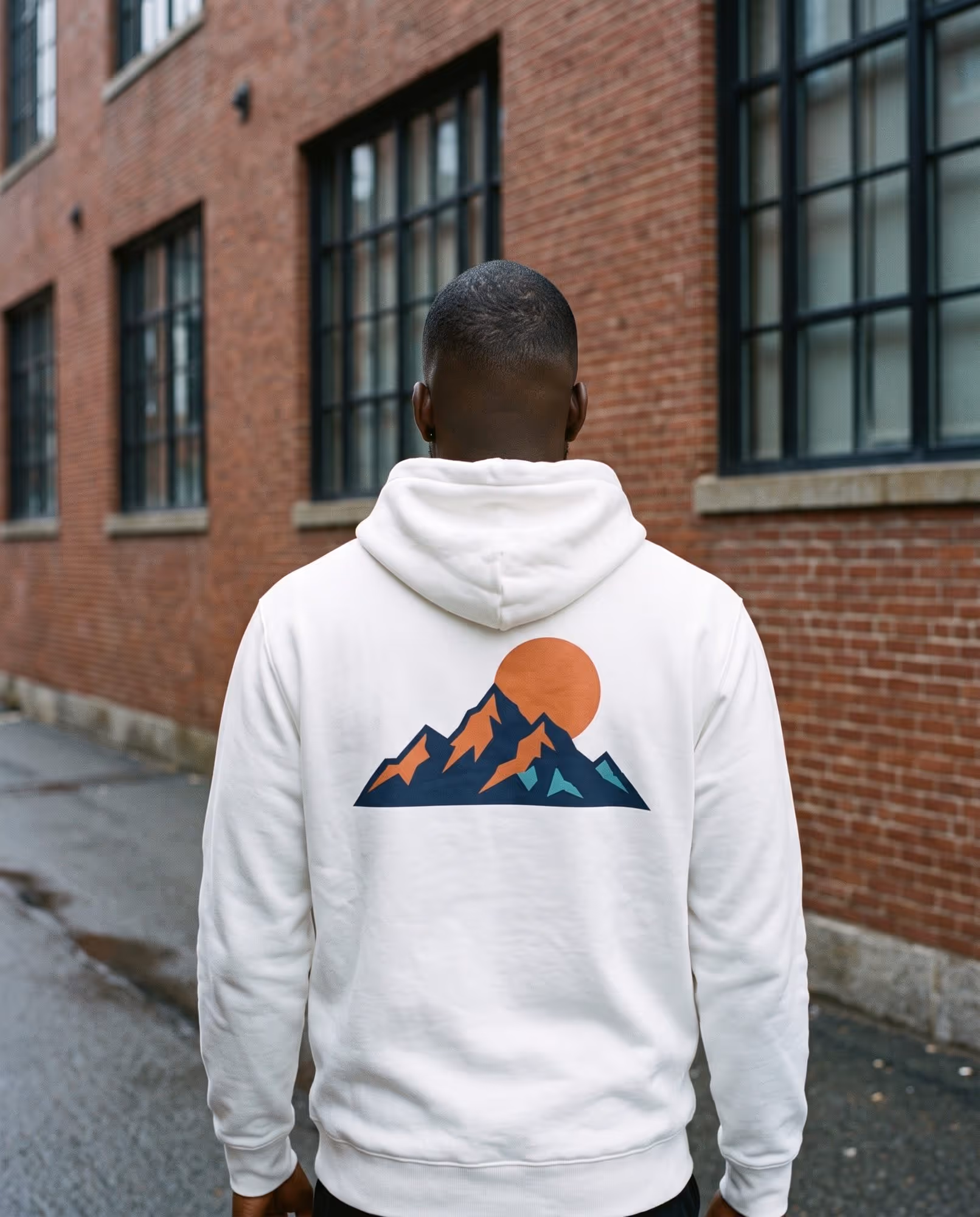 Back of a white hoodie with a large printed mountain range and sun illustration