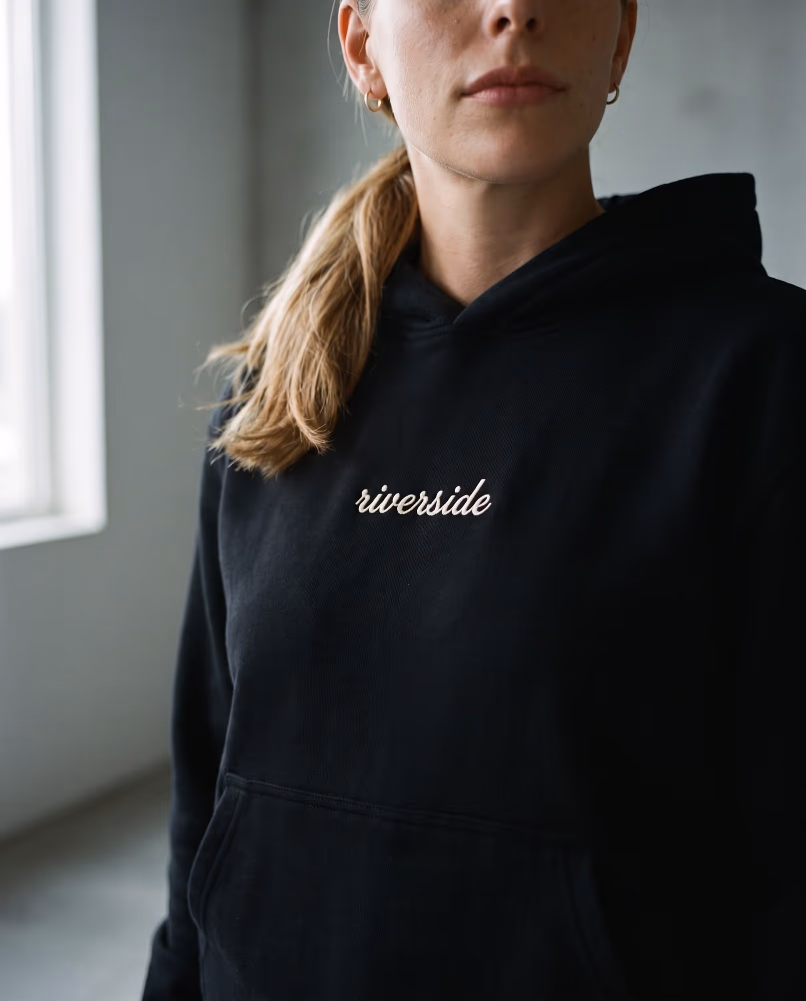 Black hoodie with "riverside" printed in cream script on the left chest