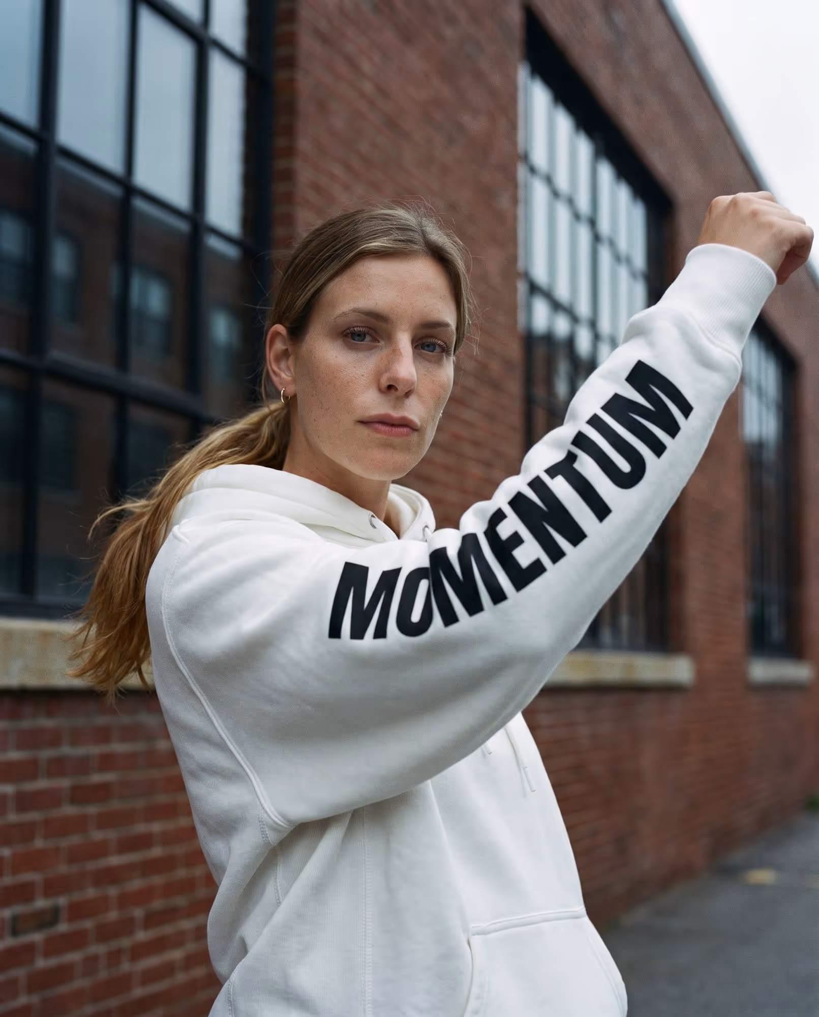 White hoodie with "Momentum" printed in black down the length of the sleeve
