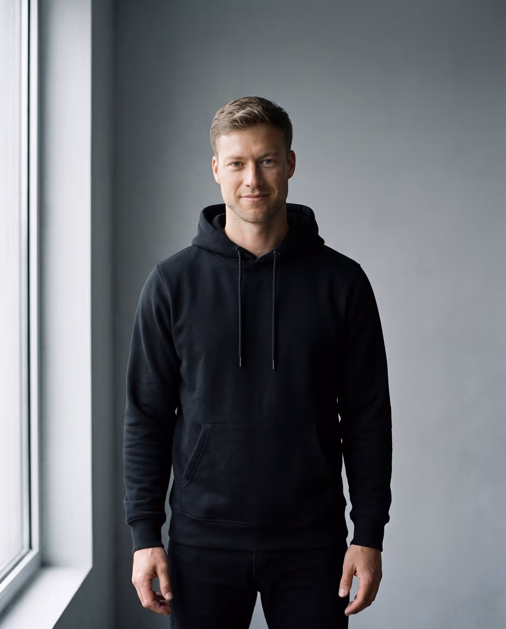Model wearing the plain black pullover hoodie blank, front view
