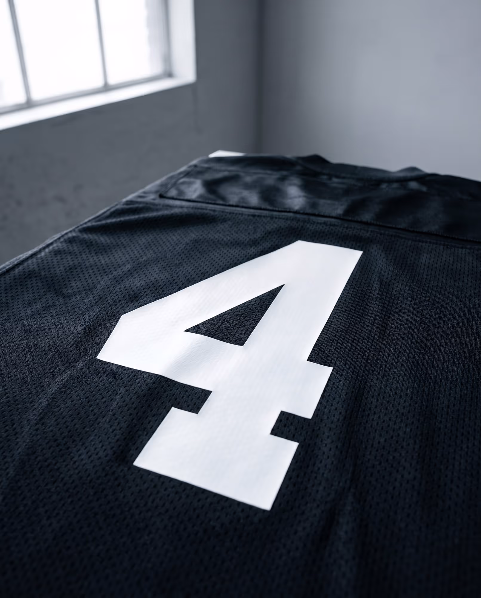 Close-up of a white heat-pressed vinyl number on black jersey mesh