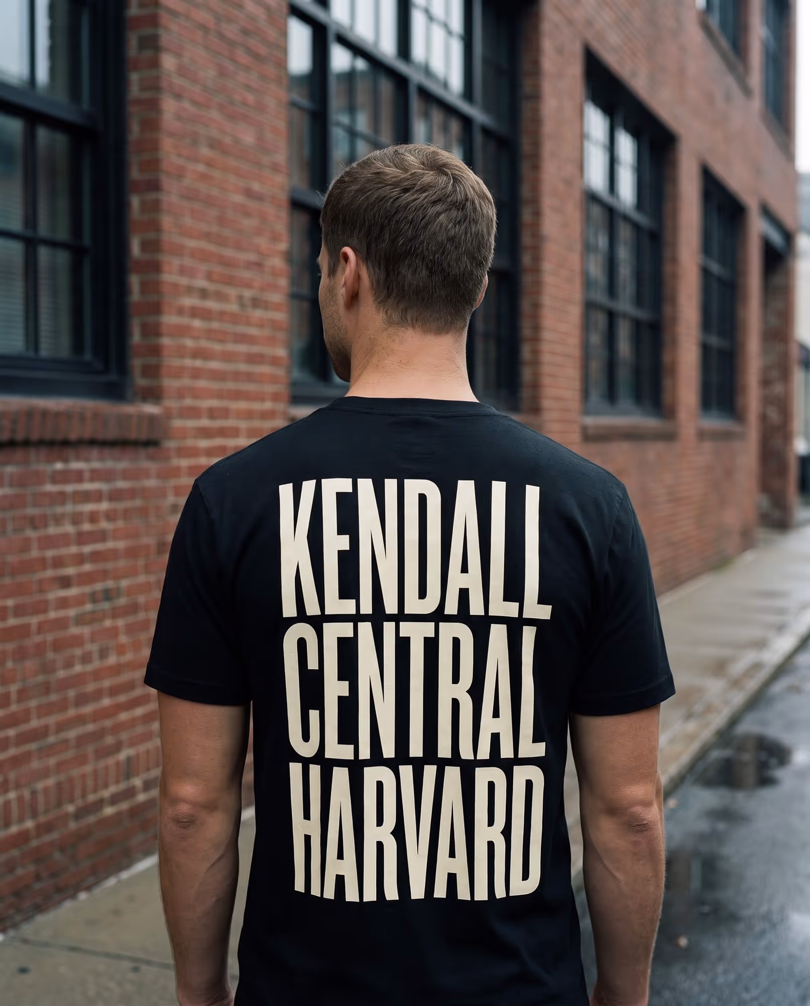 Back of a black t-shirt printed with the words Kendall, Central and Harvard stacked in tall cream type