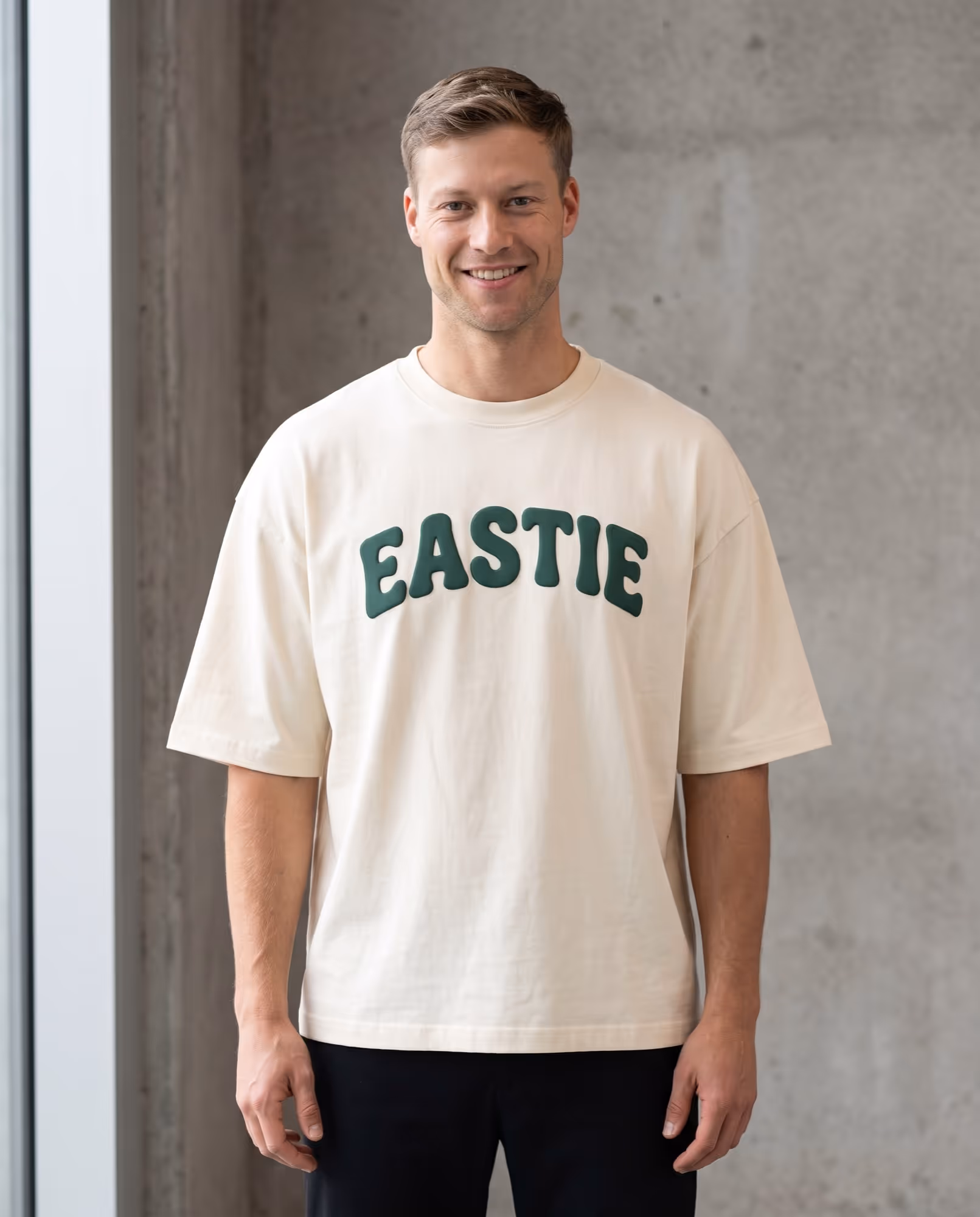 Cream oversized t-shirt with EASTIE across the chest in thick raised green lettering