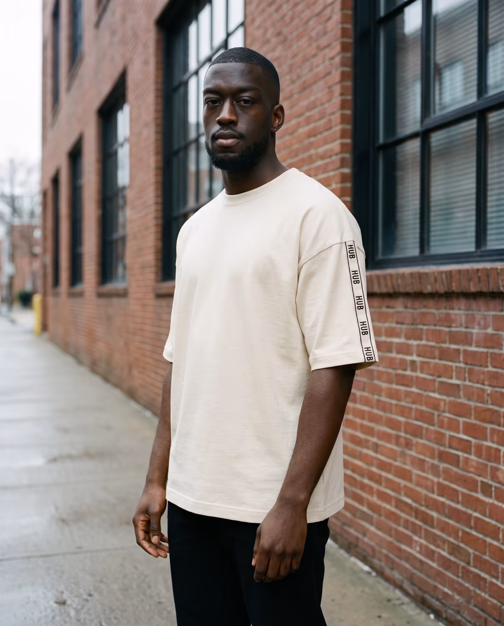 Cream oversized t-shirt with HUB repeated down a narrow black strip on the sleeve