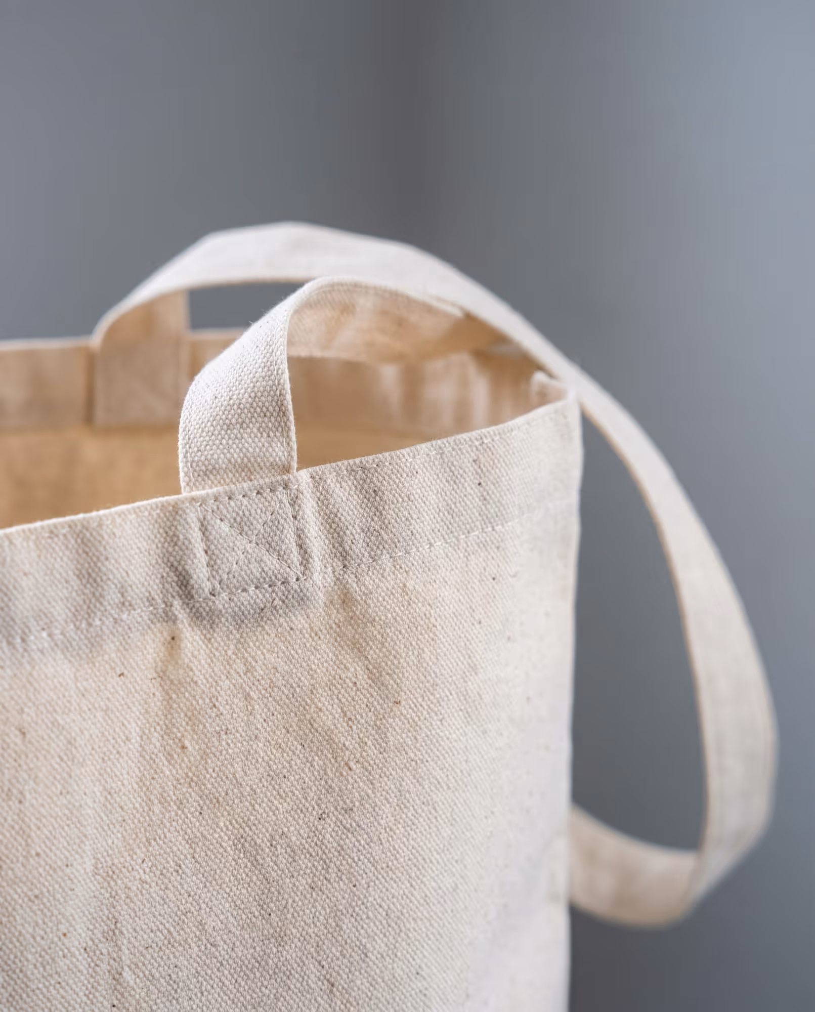 Close-up of the top-stitched hem and box-stitched strap on a natural canvas tote bag